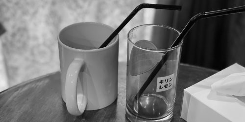 白いマグカップと”キリンレモン”という文字がプリントされている透明なコップが机の上に並んでいる白黒の写真