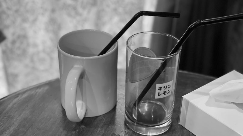 白いマグカップと”キリンレモン”という文字がプリントされている透明なコップが机の上に並んでいる白黒の写真