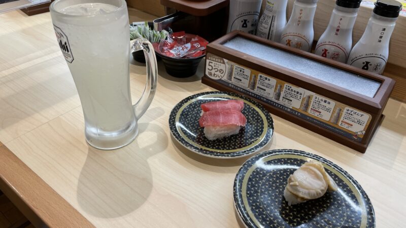 レモンサワーとマグロと帆立のお寿司が机に並んでいる写真