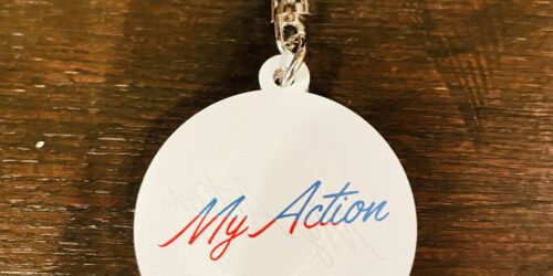 丸くて白い形に“My Action”と文字がプリントされているキーホルダー