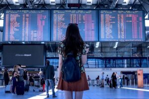 女性が空港でフライトの時間と便が表示されているモニターを見ている写真