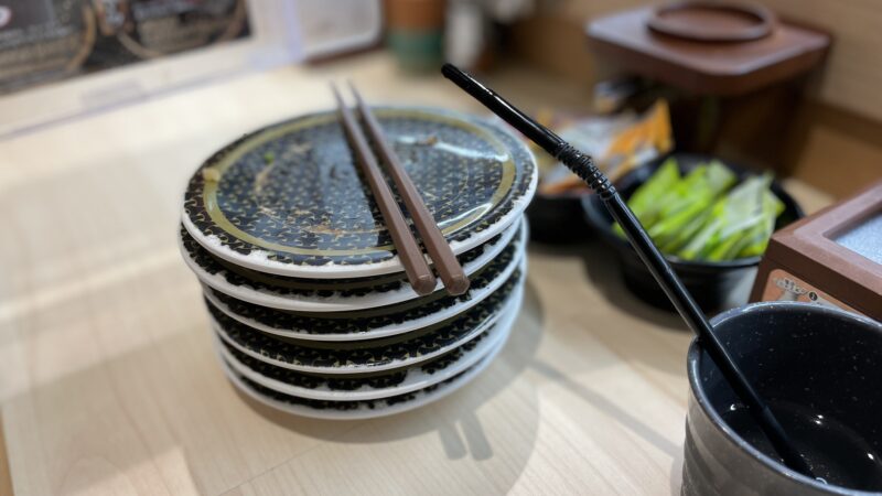 回転寿司で6皿を食べて、机の上に空いたお皿が重なっている写真