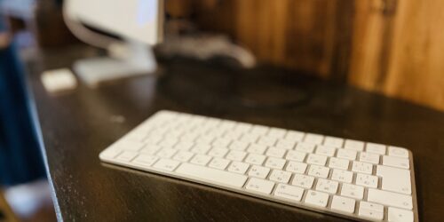 机の上にMacのキーボードが置いてある写真