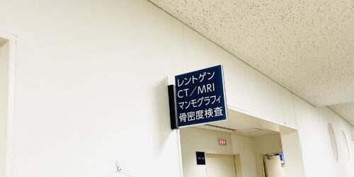 青い看板に白い字で、レントゲン・CT/MRI・マンモグラフィ・骨密度検査と書いてあるプレートが写っている写真
