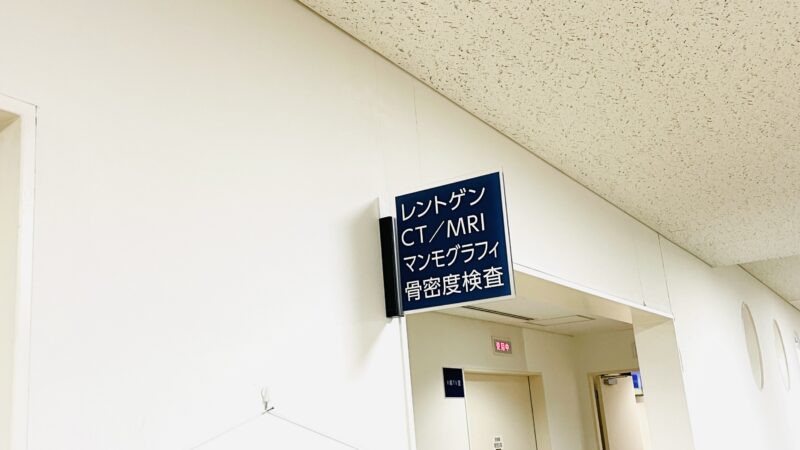 青い看板に白い字で、レントゲン・CT/MRI・マンモグラフィ・骨密度検査と書いてあるプレートが写っている写真
